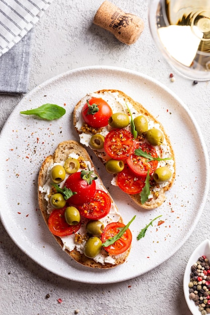 Bruschettas mit Oliven und frischen Tomaten und Weinglas