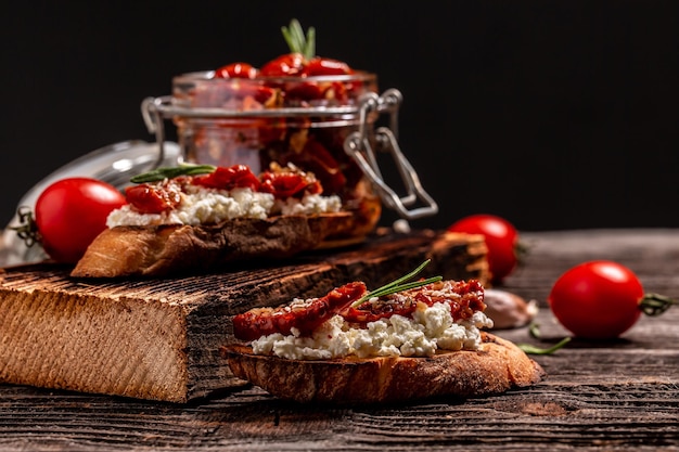 Bruschettas mit sonnengetrockneten Tomaten und Ricotta-Diätkäse auf Holzhintergrund.