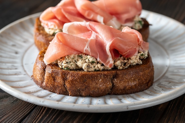 Bruschettas con queso crema, tomates secos y jamón serrano en el plato