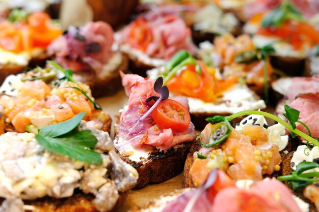 Bruschettas variadas em uma bandeja de madeira Carne de peixe legumes e ervas Lanches apetitosos Closeup