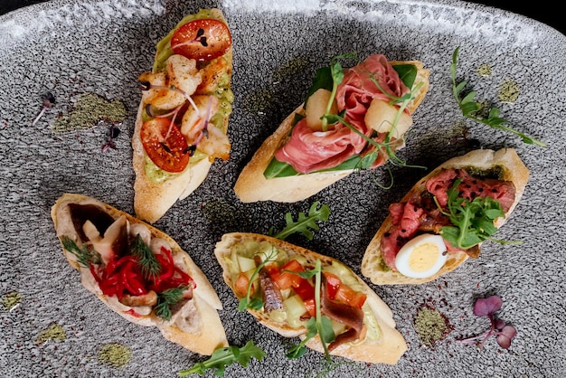 Foto brusquetas ovaladas con diferentes rellenos en un plato ovalado gris