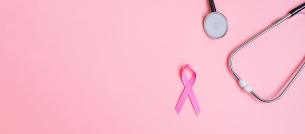 Brustkrebs-Bewusstsein, Pink Ribbon mit Stethoskop auf rosa Hintergrund zur Unterstützung von Menschen, die leben und krank sind. Konzept für Frauengesundheit und Weltkrebstag