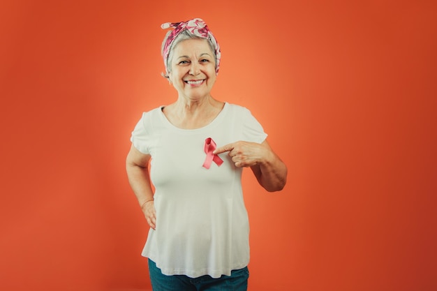 Brustkrebs-Schutzsymbol Reife Frau mit rosa Schleife auf und weißem T-Shirt isoliert für Brustkrebskampagne