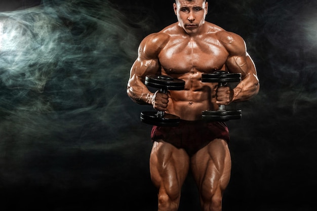 Brutal culturista musculoso fuerte hombre atlético bombeando músculos con pesas en fondo negro concepto de culturismo de entrenamiento Copiar espacio para anuncios de nutrición deportiva