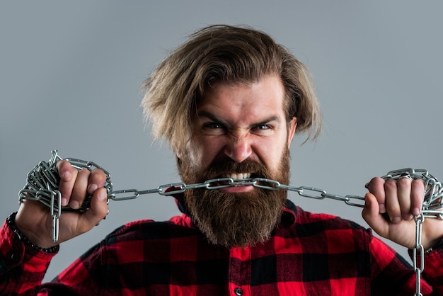 Brutal hombre barbudo mordiendo cadena de acero con dientes fuertes corrección de mordida