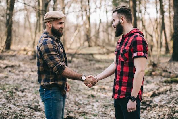 Brutal homens apertando as mãos na floresta