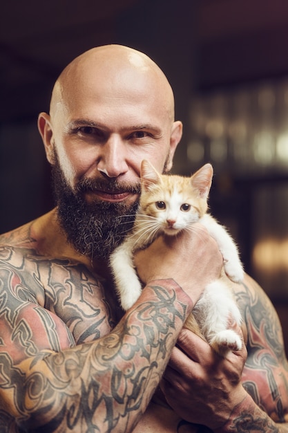 Brutal tätowierter bärtiger Mann mit Katze im Fitnessstudio