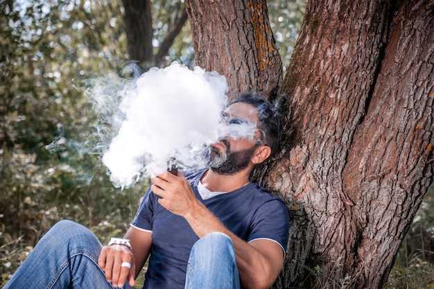 Foto brutal vaper libera una nube de vapor. cigarrillo híbrido.