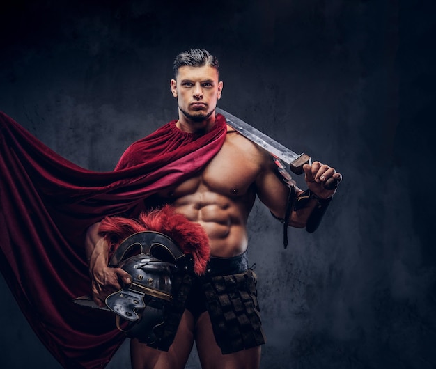 Brutaler altgriechischer Krieger mit muskulösem Körper in Kampfausrüstung, der auf dunklem Hintergrund posiert.