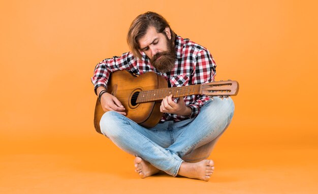 Brutaler bärtiger Mann trägt kariertes Hemd mit üppigem Bart und Schnurrbart und spielt Gitarrenmusik