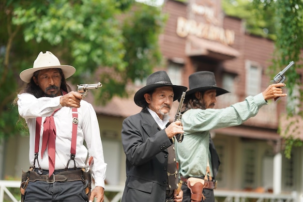 Brutaler Cowboy mit Revolverschießerei auf ländlichem Hintergrund der Ranch