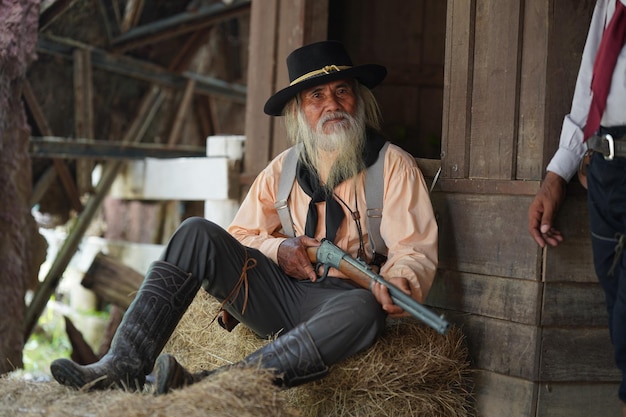 Foto brutaler cowboy mit revolverschießerei auf ländlichem hintergrund der ranch