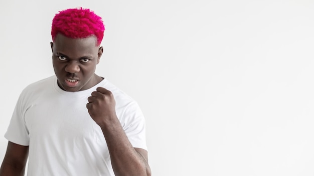 Brutaler Mann Black Lives Matter Bedrohungsgeste Straggle-Opposition Sozialer Druck Werbehintergrund Aggressiver afrikanischer Kerl mit rosa Haaren, die die Faust ballen, isolierter weißer Kopierraum