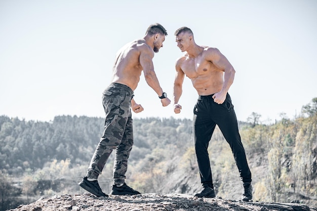 Brutales culturistas fuertes entrenando músculos entre sí Concepto de culturismo y deportes al aire libre Dos atletas masculinos