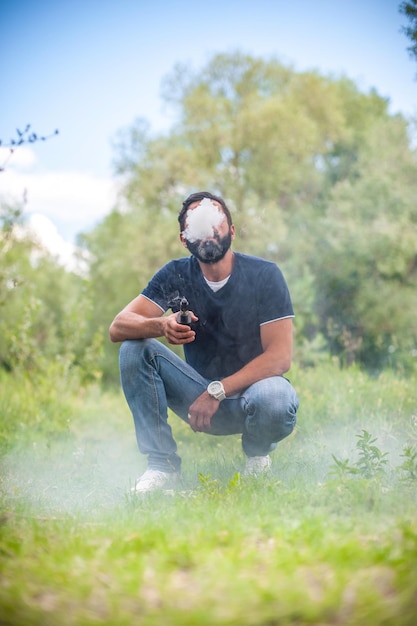 Brutalvaper elegante desfrutando de um cigarro eletrônico no chão da floresta. Homem bonito.