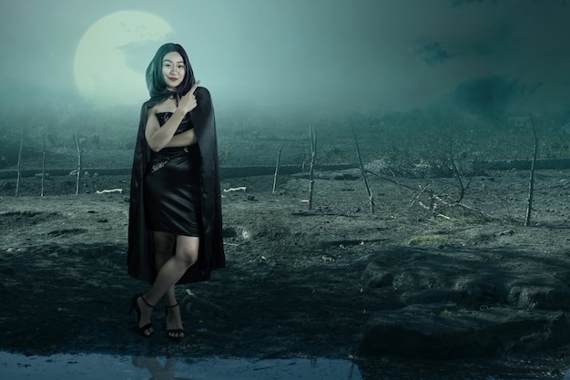 Bruxa asiática com uma capa apontando algo com o campo assombrado