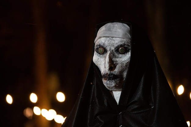 Bruxa assustadora de halloween com olhos vermelhos em um manto preto em um  ambiente sombrio