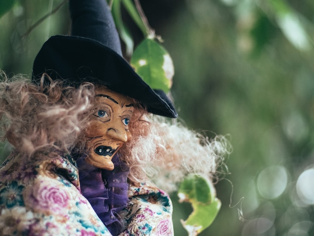 Bruxa malvada em fundo escuro da natureza, retrato de uma senhora idosa com maquiagem terrível, plano de fundo de Halloween