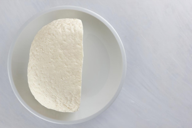 Brynza macio branco ou queijo feta em um prato branco sobre um fundo branco Conceito de comida vegetariana Closeup Vista de cima