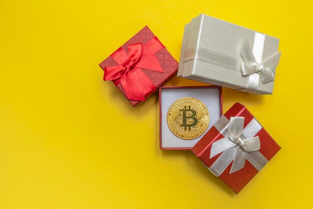 BTC-Geschenk. Bitcoin-Münze in einer roten Geschenkbox auf gelbem Hintergrund. Postkarte zum Drucken, Banner mit Platz für Text.