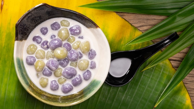 Bualoy, Bua Loy, Bualoi, Bua Loi, Thai-Dessert, Klebreis-Knödel in süßer Kokosmilch, violette Farbe von Taro, grüne Farbe von Pandan-Blatt auf Bananenblatt, Draufsicht, Full-HD-Verhältnis