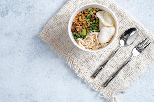 Bubur ayam, gachas de arroz de Indonesia con pollo desmenuzado sobre fondo blanco.