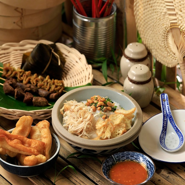 Bubur Ayam o gachas de arroz chino indonesio con pollo desmenuzado. Servido con Kerukpuk (Cracker), Salsa de Soya, Frijoles de Soya Fritos y Sambal