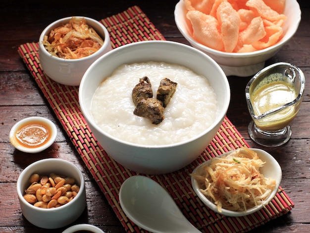 Bubur Ayam o gachas de arroz de Indonesia con pollo desmenuzado. Servido con Kerukpuk (Cracker), Salsa de Soya, Frijoles de Soya Fritos y Sambal