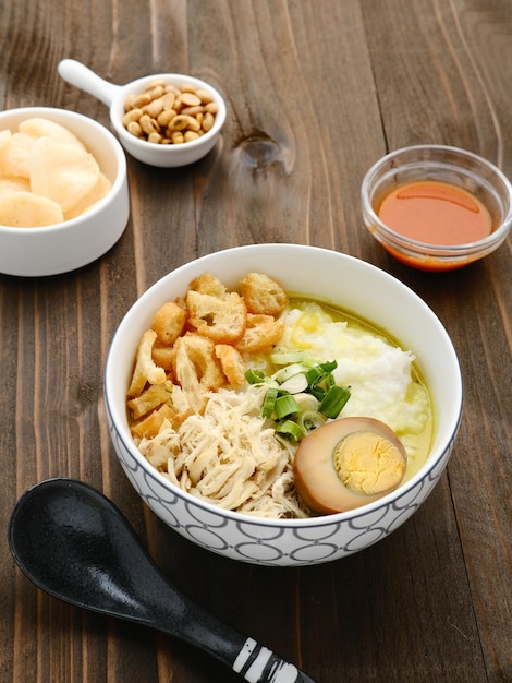 Bubur Bubur Ayam Mingau de arroz indonésio servido com frango desfiado e ovo Foco seletivo