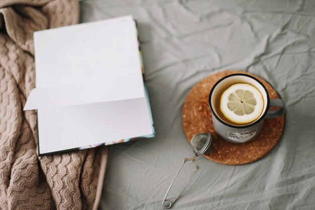 Buch und eine Tasse Zitronentee im warmen, weichen Bett