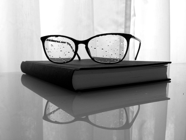 Buch und nasse Brille auf dem Tisch zu Hause