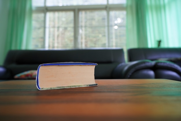 Foto buchen sie auf holztisch mit unscharfem sofa im raumhintergrund