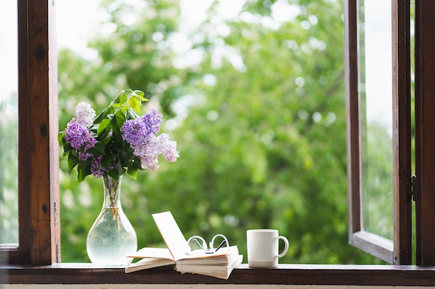 Buchen Sie Gläser Tasse Tee und Flieder auf einem Holzfenster Duftender Tee im Garten Romantisches Konzept Vintage-Stil