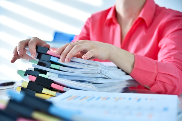Buchhalterin oder Geschäftsfrau sucht im Büro nach einem Geschäftsbericht in einem Stapel von Dokumenten.