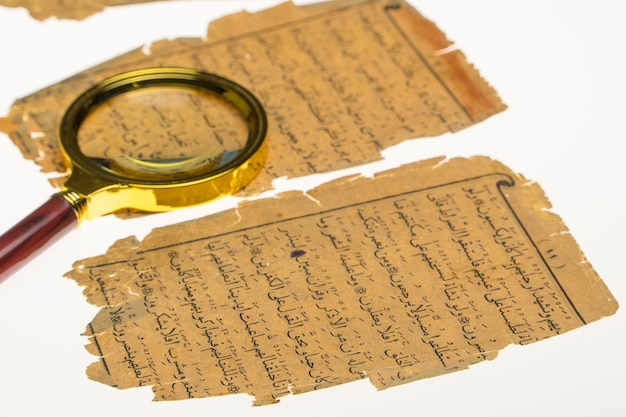 Buchseiten mit einem arabischen Manuskript auf einem Tisch mit Licht und Lupe