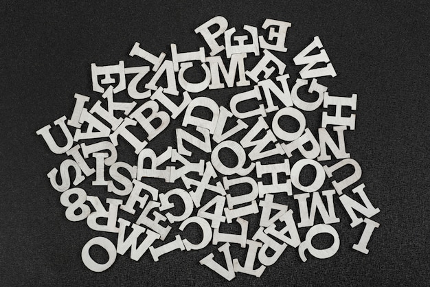 Buchstaben des englischen Alphabets in chaotischer Reihenfolge auf Schwarzraum angeordnet. Top wiev
