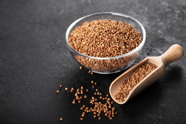 Buchweizen in Glasschale Müsli auf schwarzem Hintergrund