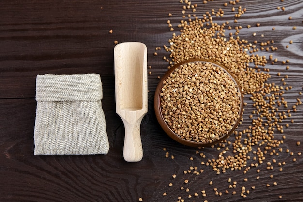 Buchweizen, Schüssel, Schaufel und Sack auf Holztisch