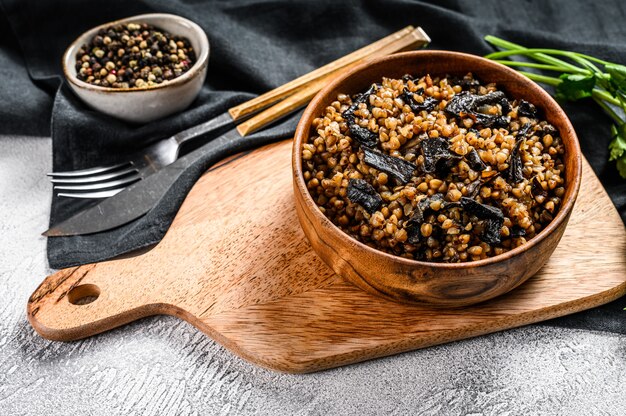 Buchweizenbrei mit Pilzen. Veganes Essen. Russische, ukrainische Küche. Grauer Hintergrund. Draufsicht