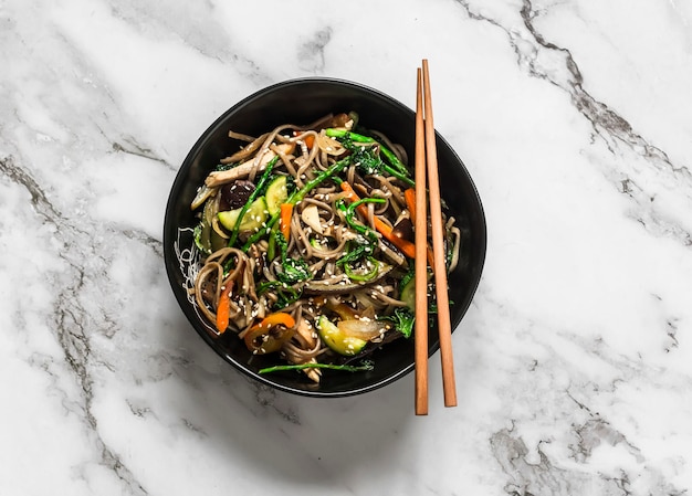 Buchweizennudeln mit Hühnergemüse und Pilzen köstliches Mittagessen im asiatischen Stil auf hellem Hintergrund Draufsicht