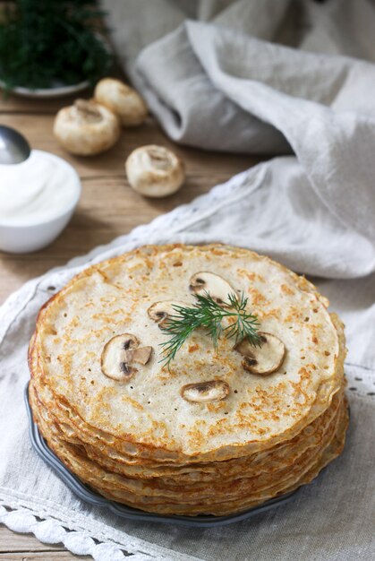 Buchweizenpfannkuchen dienten mit Sauerrahm und Dill auf einem Holztisch.