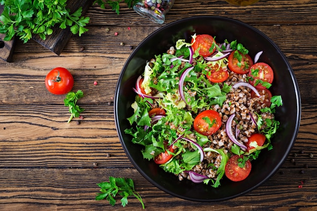 Buchweizensalat mit Kirschtomaten, roten Zwiebeln und frischen Kräutern. Veganes Essen.