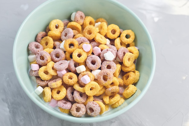 Bucles de frutas de cereales multicolores en un recipiente sobre fondo gris cerca de espacio de copia concepto de desayuno