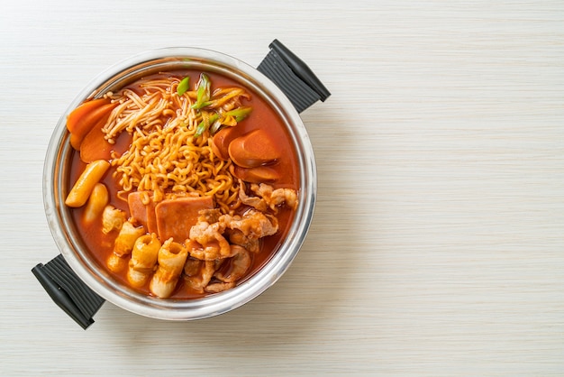 Budae Jjigae o Budaejjigae (estofado del ejército o estofado de base del ejército). Está cargado de kimchi, spam, salchichas, fideos ramen y mucho más.