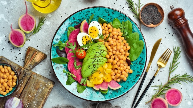 Buddha Bowl Kichererbsen Avocado Ei Wassermelone Rettich und Spinat Köstliches ausgewogenes Ernährungskonzept auf Steinhintergrund