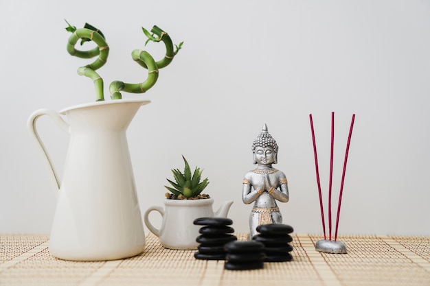 Foto buddha-figur mit schwarzen steinen, weihrauch und vegetation