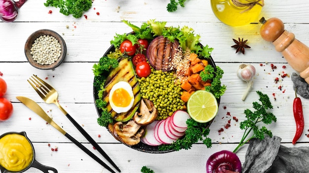 Buddha-Schüssel Avocado Mungbohne Kürbis Pilze Tomaten und Salat in einer schwarzen Schüssel Vegane Ernährung Draufsicht Freier Platz für Text