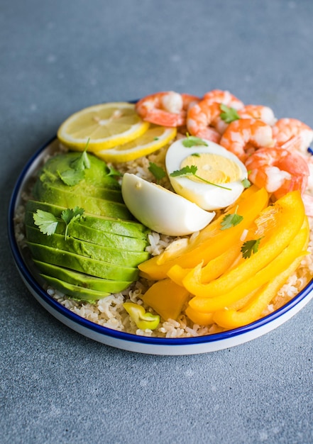 Foto buddha-schüssel mit avocado, garnelen, reis auf hellem hintergrund, gesunde nahrung, sauberes essen, buddha-schüssel, top-view