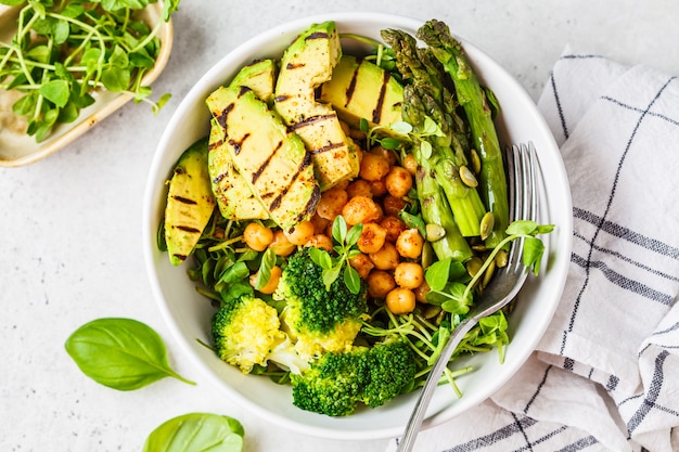 Foto buddha-schüssel mit gegrillter avocado, spargel, kichererbsen, erbsensprossen und brokkoli