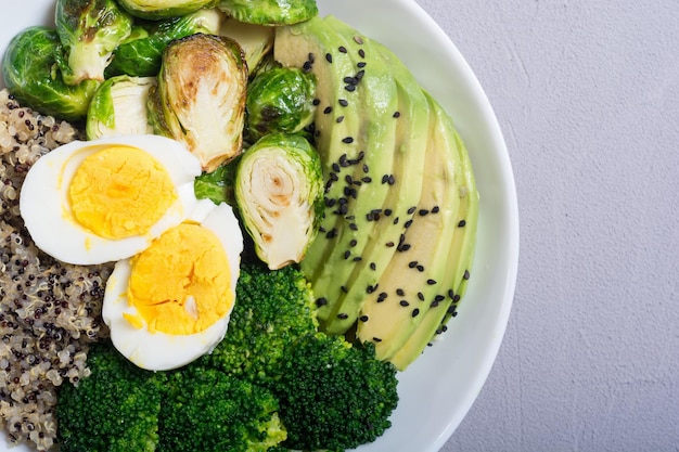 Buddha-Schüssel mit Quinoa-Eiern, Avocado-Rosenkohl und Brokkoli. Veganer Salat auf Holzhintergrund